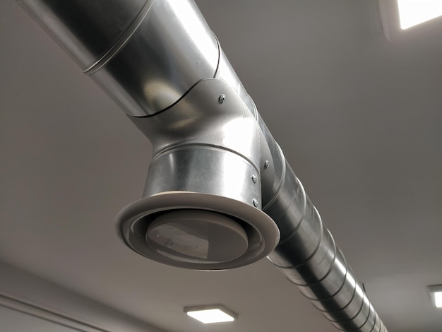 Extractor hood in a public toilet Round metal pipe with gray air extractor Engineering ventilation