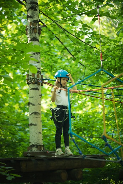 Extreem touwavontuur in het bos een klein meisje dat op de standaard aan de boom staat en op hulp wacht