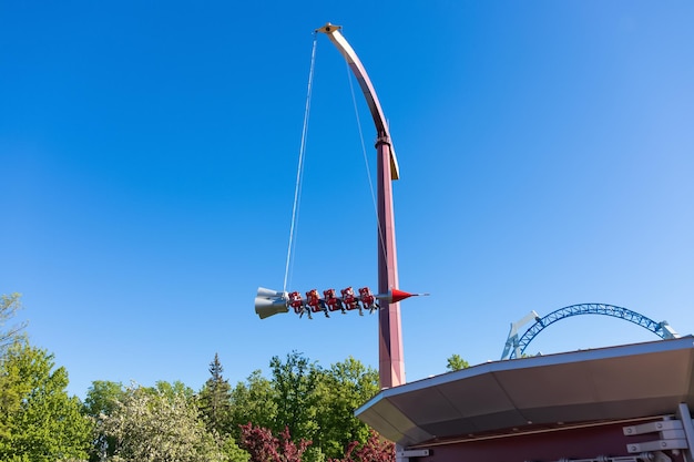 Extreme attraction rocket against blue sky above green trees and roof