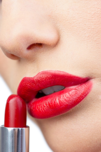 Extreme close up on gorgeous red lips being made up