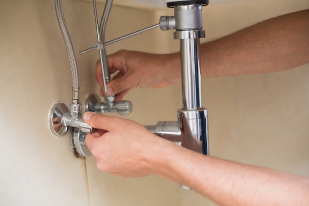 Extreme Close up of a plumbers hands and washbasin drain