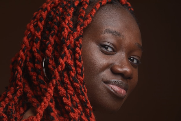 Extreme close up ritratto di elegante giovane donna afro-americana con i capelli intrecciati che guarda l'obbiettivo mentre posa in studio