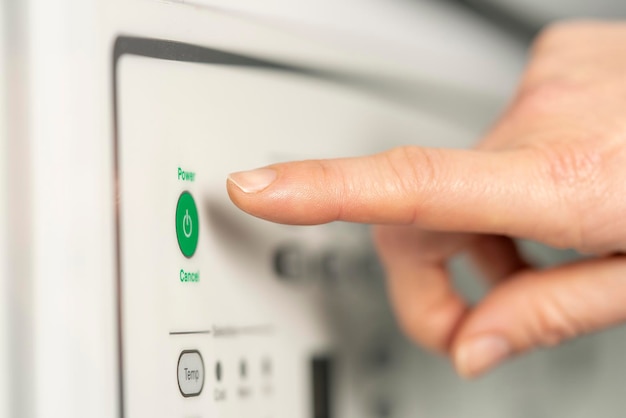 Extreme close-up van een hand die op het punt staat op de groene startknop van de wasmachine te drukken