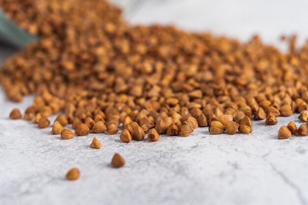 Extreme closeup buckwheat grain poured from glass jar on gray table Selective focus