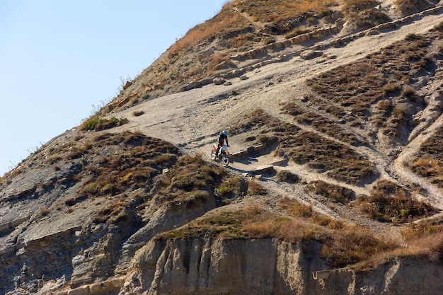 Photo extreme enduro motorcycle driving a young guy drives down a steep mountain
