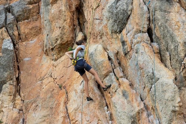 Extreme girl rock climber on a sheer grayred rock in the Crimean mountains