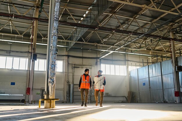 Photo extreme long shot of two young male engineers or technicians with blueprint