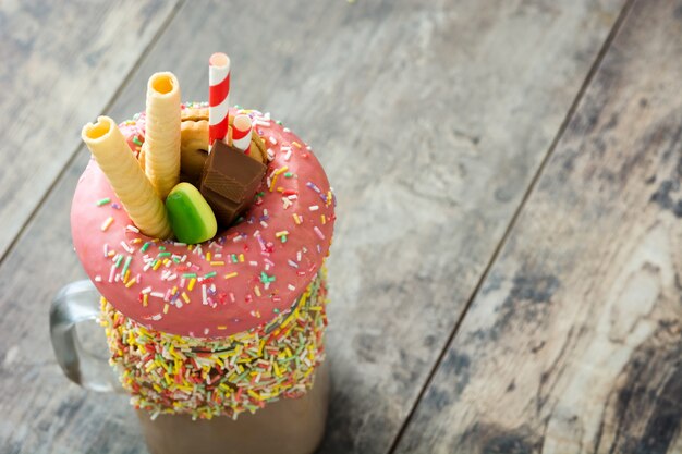 Extreme milksake or freak shake on wooden table,