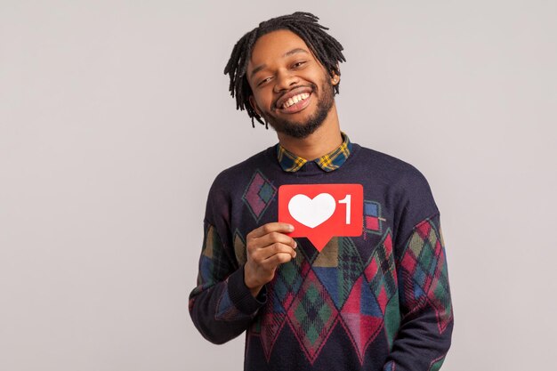 Extremely excited african blogger holding heart like counter symbol with toothy smile on face, satisfied proud of popularity in internet