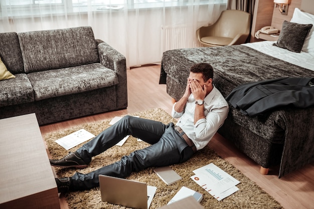 非常に疲れています。彼のホテルの部屋で一日中働いた後、非常に疲れを感じている若い賢い成功した男