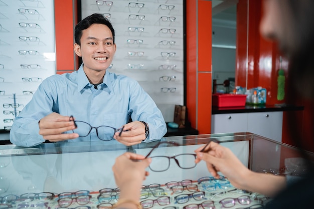 안과 진료소 직원이 안과 진료소에서 사용할 안경을 선택할 때 여성 소비자에게 서비스를 제공하고 있습니다.