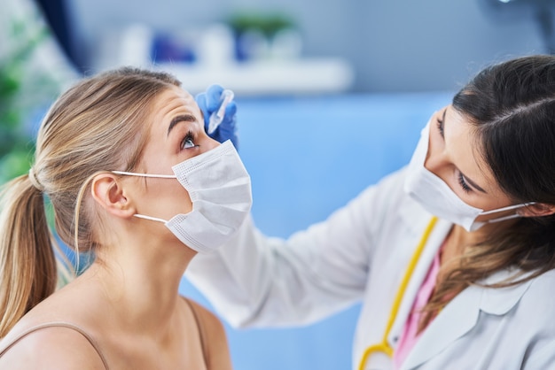eye-doctor in mask checking up on female patient