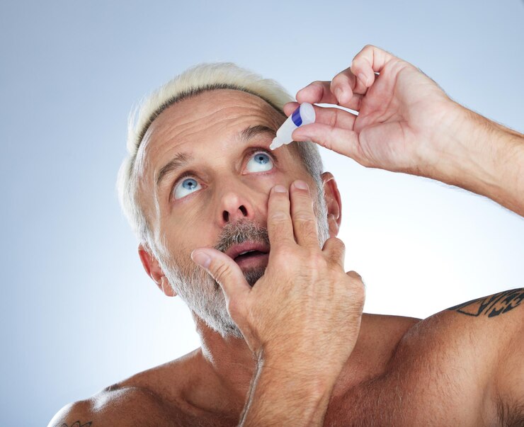 Photo eye drops senior man and studio with medical healthcare and wellness pharmaceuticals isolated blue background and male model with dry eyes and medicine for vision solution and allergy product