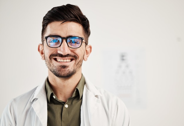 Улыбка при осмотре глаз и портрет мужчины-офтальмолога в очках уверенности и дружелюбное обслуживание в консультационном кабинете Лицо офтальмолога и счастливый эксперт-мужчина, гордящийся своей карьерой в тестировании зрения