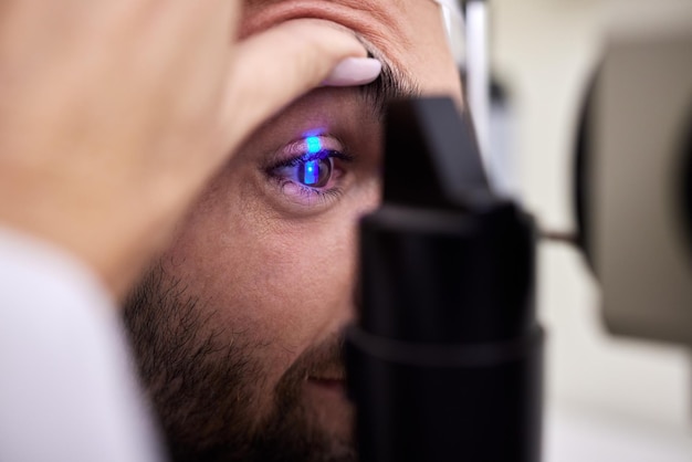 Vista dell'esame oculistico o test laser per un uomo con macchina alla consultazione di optometria per problemi alla retina vista delle mani o medico che aiuta o controlla un paziente o un cliente con un'assicurazione medica per la salute