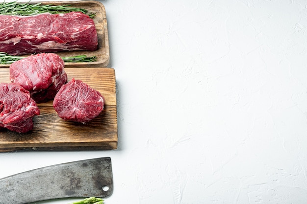 Eye Fillet beef marbled fresh meat steak set, and old butcher cleaver knife, on wooden cutting board, on white stone surface