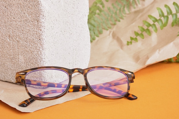 Eye glasses on a concrete podium on a brown background, trend composition, stylish eye glasses