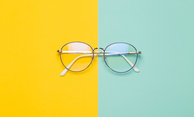 Photo eye glasses isolated on yellow and blue surface.