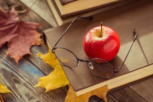 Eye glasses with book and autumn leaves on table