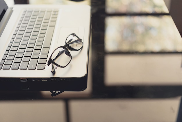 Eye glasses on work desk with chart and laptop at business workplace.