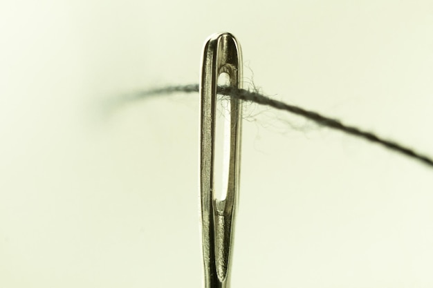 The eye of a needle with a thread closeup