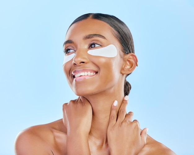 Photo eye patch face and beauty of a happy woman with natural skin glow on a blue background dermatology collagen mask and cosmetics of indian person for facial shine wellness or self care in studio