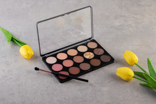 Eye shadow cosmetics with brush and yellow tulips.