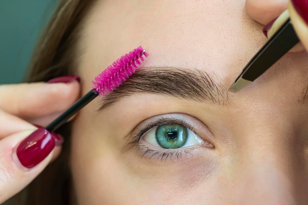 Eyebrow correction in a beauty salon combing eyebrows beautiful young woman in cosmetic salon close up