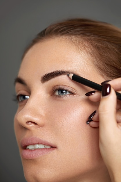 Foto trucco per sopracciglia. bello modello che modella le sopracciglia con il primo piano della matita della fronte. donna di bellezza con sopracciglia di contorno trucco professionale