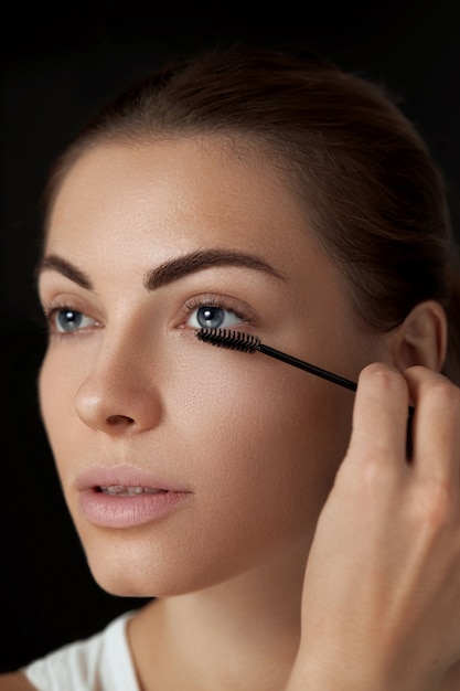 Eyebrow makeup. Beautiful woman shaping brows with eyebrow brush closeup