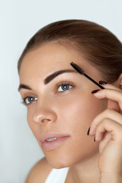 Eyebrow makeup.  Beauty model shaping brows with brush eyebrow closeup