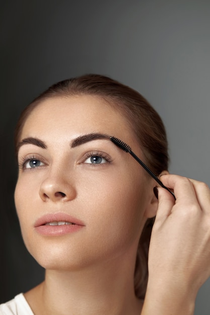 Eyebrow makeup. beauty model shaping brows with brush eyebrow\
closeup