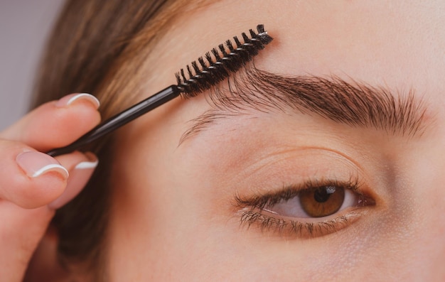 Foto trucco per le sopracciglia donna che spazzola le sopracciglia con il primo piano della spazzola delle sopracciglia macro close up of brows