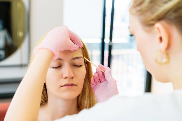 Photo eyebrow master while removing facial hair with wax skin and hair care