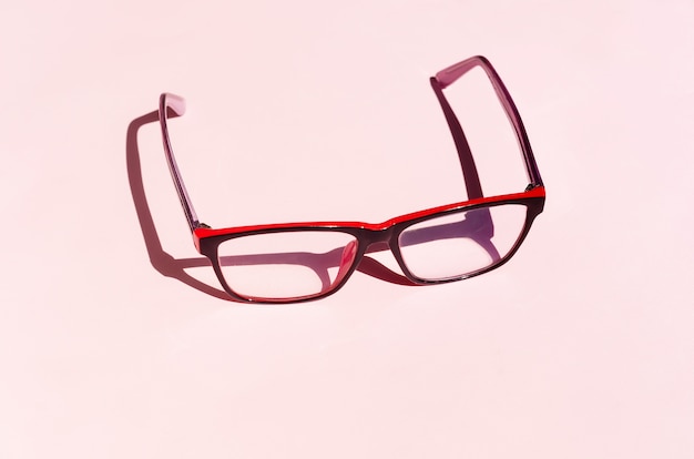 Eyeglass on pink background with shadows