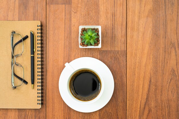 Eyeglasse и блокнот с чашкой кофе на деревянной палубе