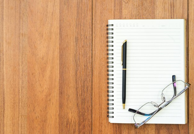 Eyeglasse and notepad on wood deck