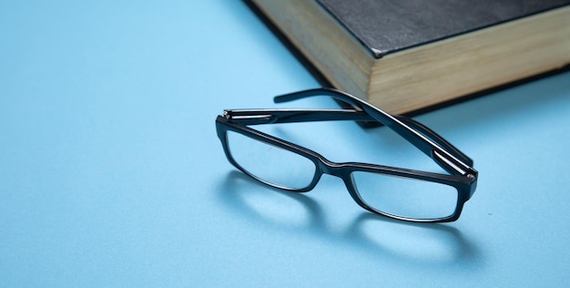 Eyeglasses and book on the blue background