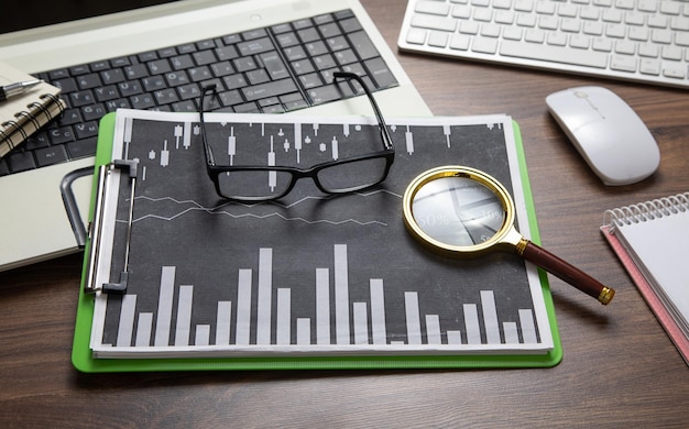 Photo eyeglasses magnifying glass financial graphs on the table