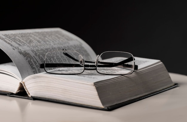 Eyeglasses and open book on black background