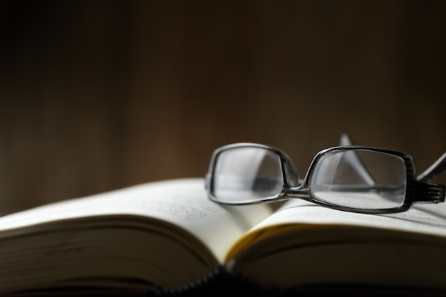 Eyeglasses on open book, education concept and dark tone