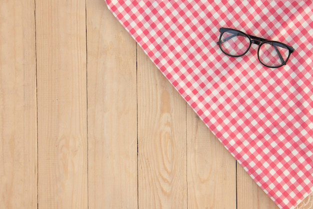 Eyeglasses over red plaid on wood