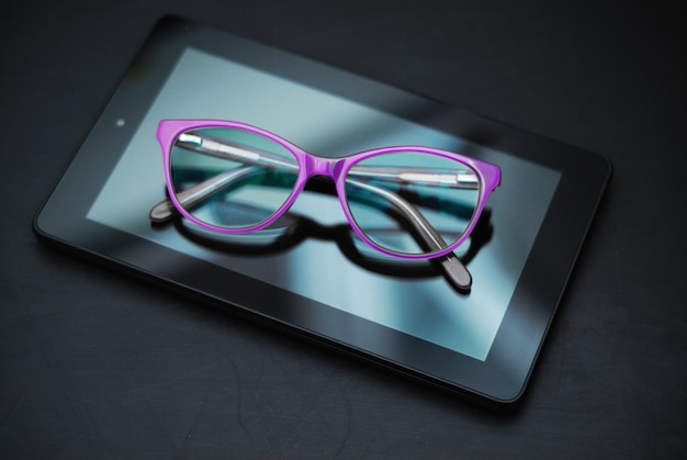 Foto occhiali da vista su tablet nel buio. educazione, technoogy, internet.