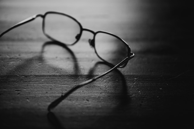 Foto occhiali da vista sul tavolo di legno, foto ravvicinata. bianco e nero.