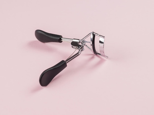 Eyelash curlers on a light pink background