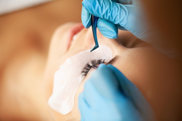 Eyelash extension procedure, professional stylist lengthening female lashes.