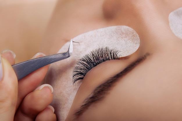 Eyelash extension procedure woman eye with long blue eyelashes ombre effect close up selective focus