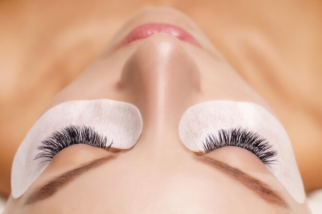 Eyelash extension procedure woman eye with long eyelashes close up selective focus