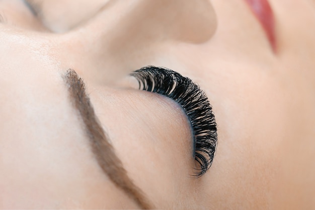 Photo eyelash extension procedure. woman eye with long eyelashes. close up