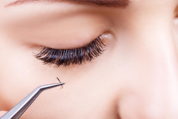 Eyelash extension procedure woman eye with long eyelashes lashes close up macro selective focus